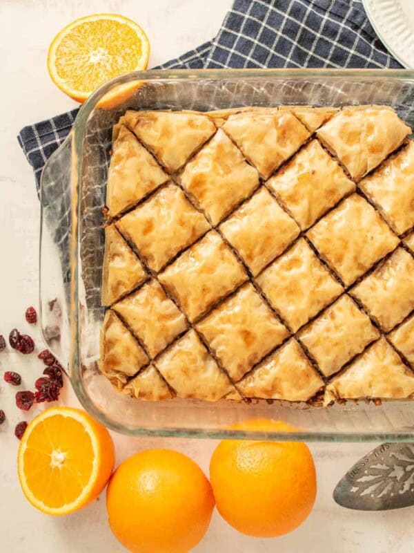 top view of baklava in a pan with oranges and cranberries around the dish