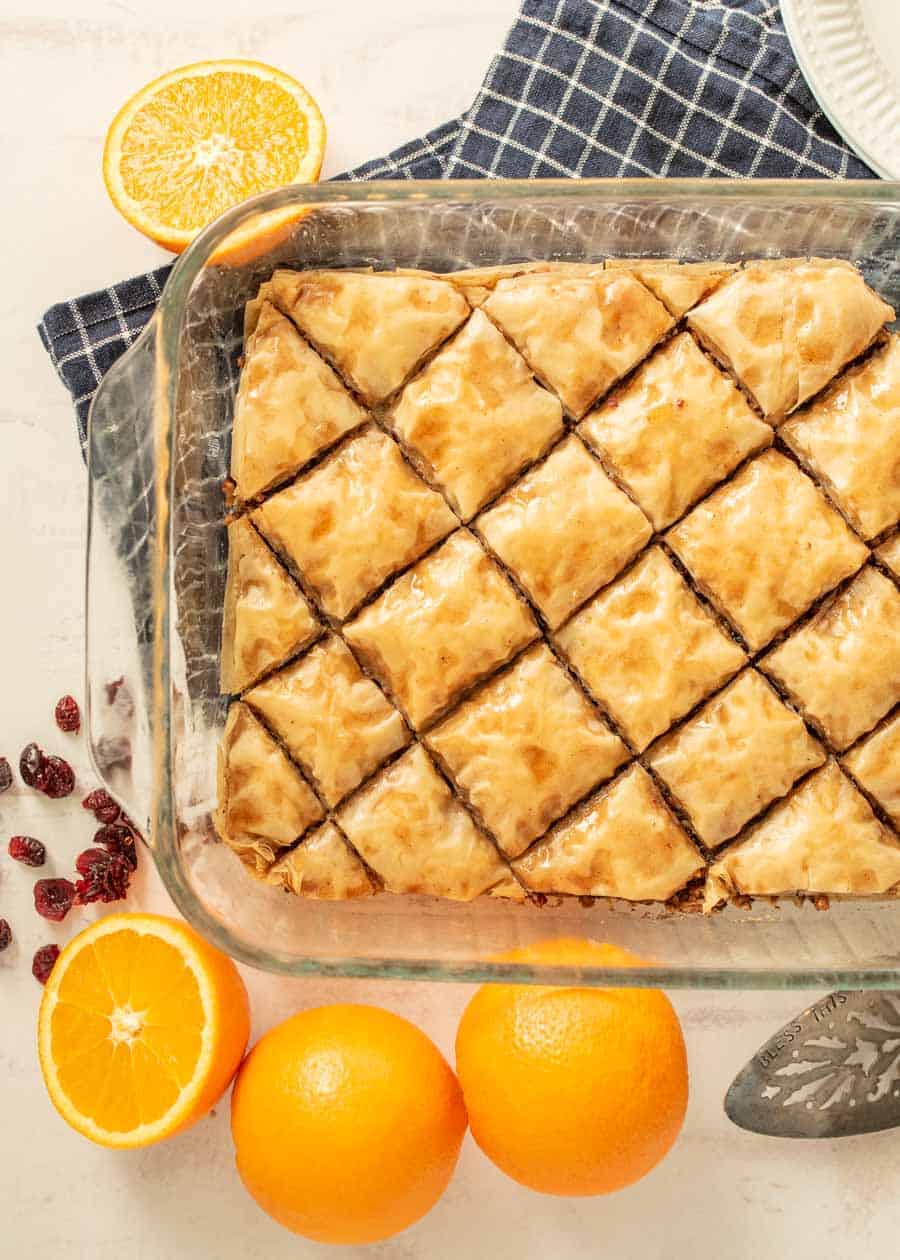 top view of baklava in a pan with oranges and cranberries around the dish