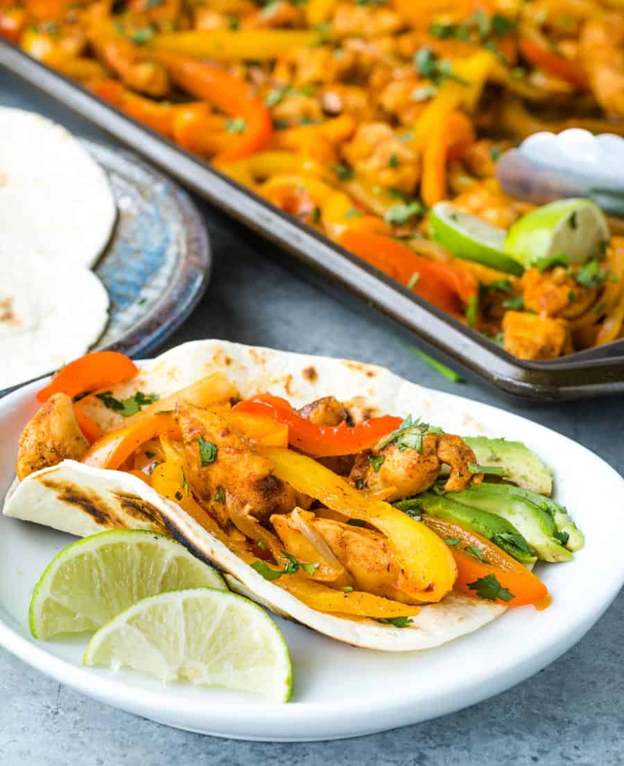 A close up of a plated fajita on a tortilla with limes.