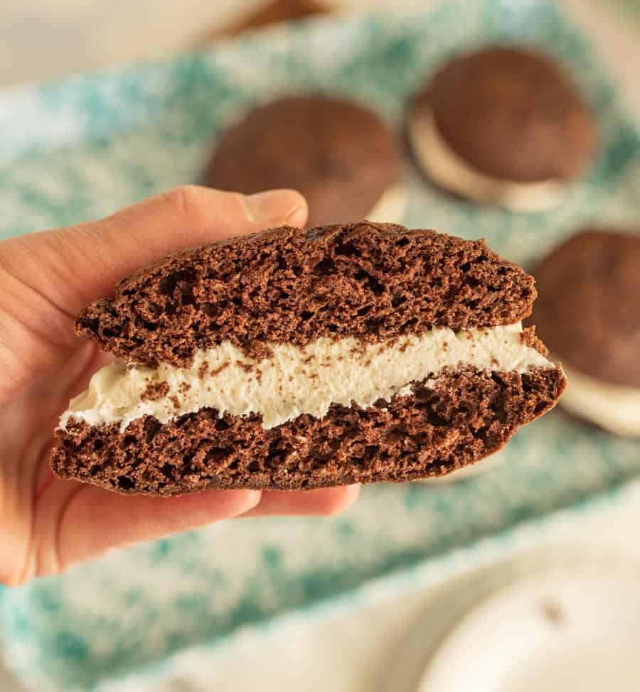 close up of a hand holding a whoopie pie cut in half