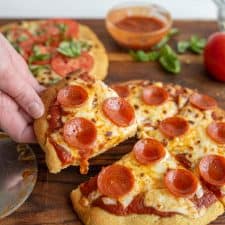 picture of a hand taking a slice of gluten free pepperoni pizza