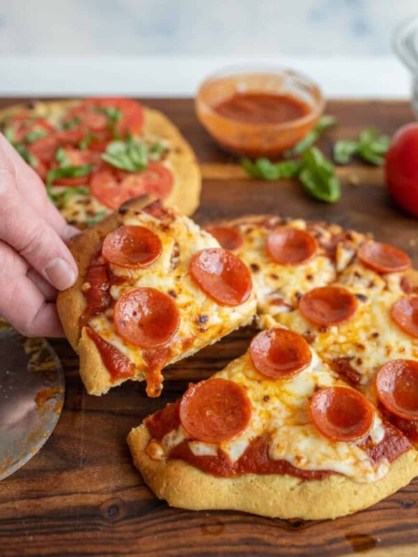 picture of a hand taking a slice of gluten free pepperoni pizza