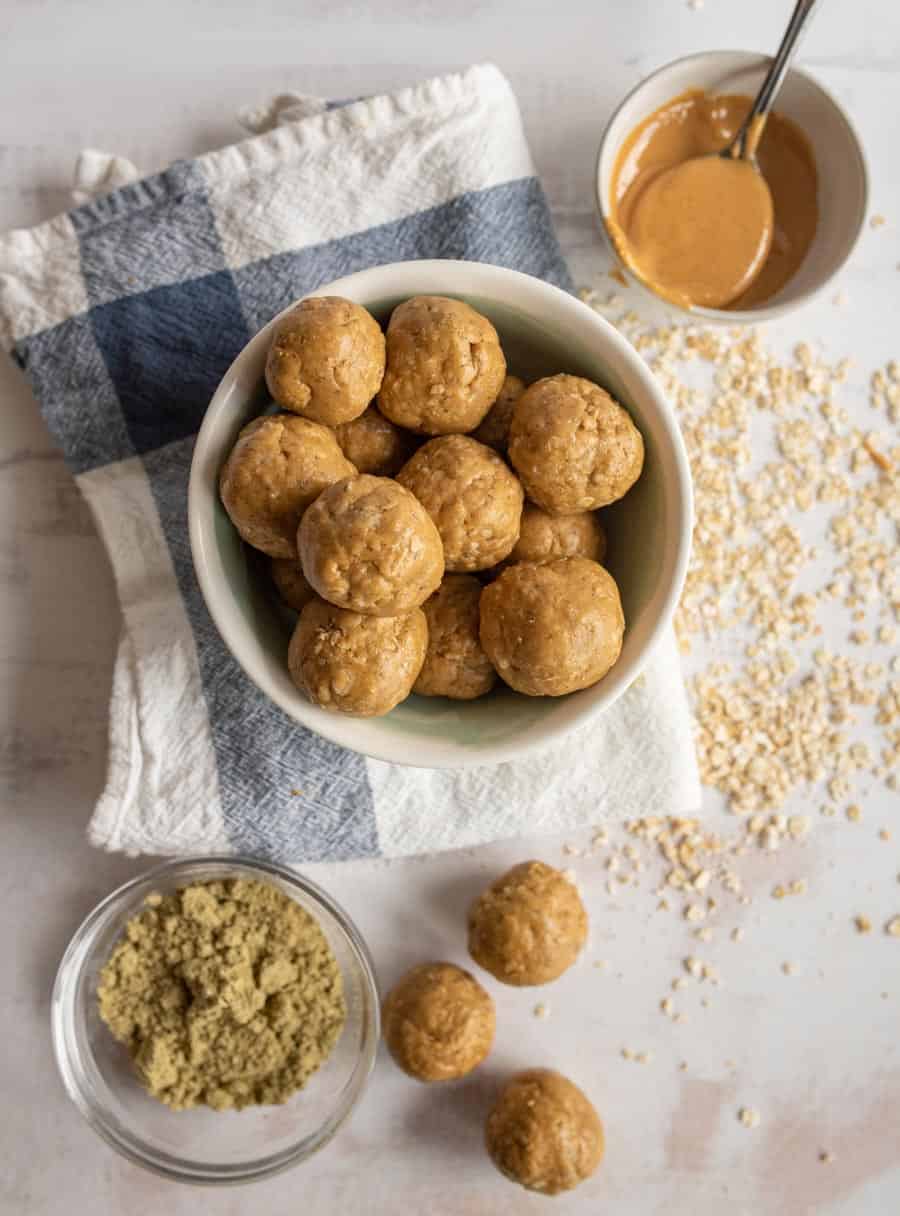 top view of peanut butter protein balls in a bowl surrounded by the ingredients for the protein balls