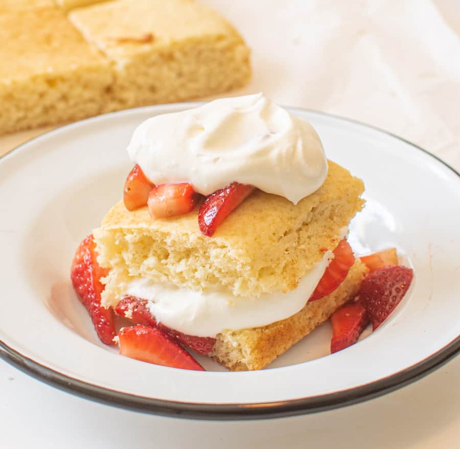 plate with cake on it with strawberries on top and whipped cream
