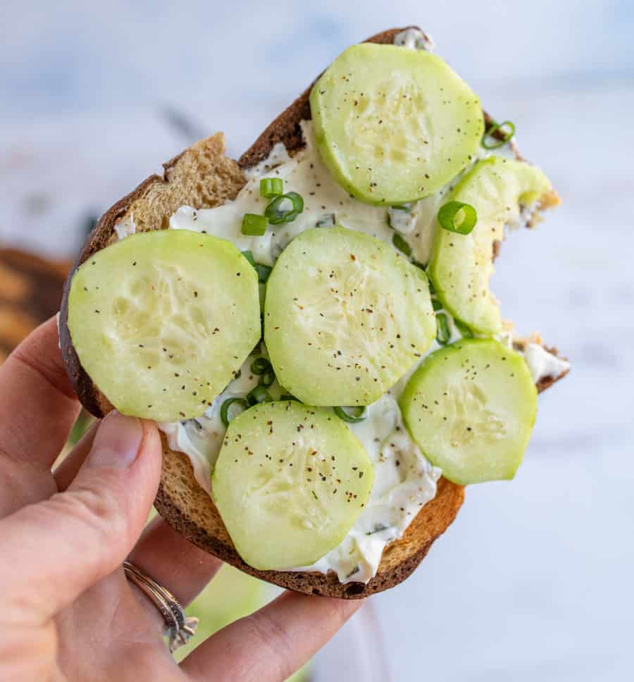 Hand holding a cucumber sandwich