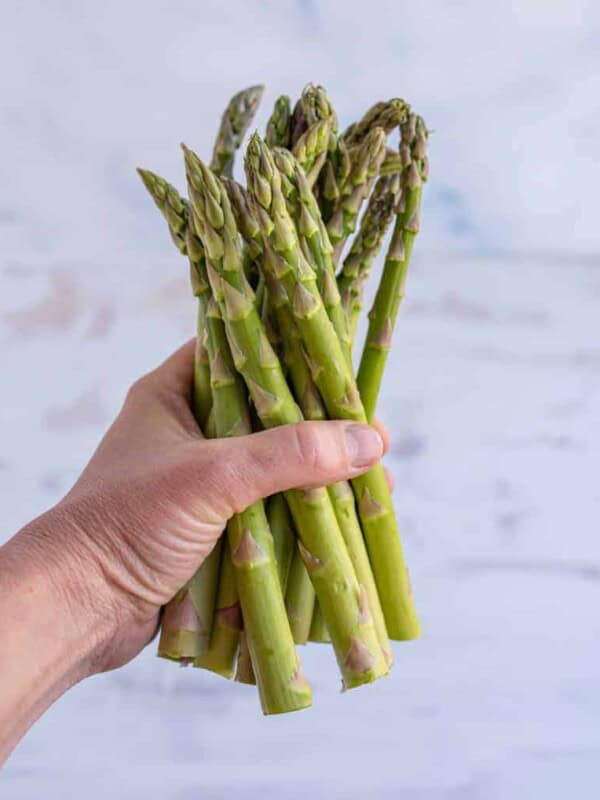 hand holding a bunch of asparagus for post teaching how to preserve asparagus.