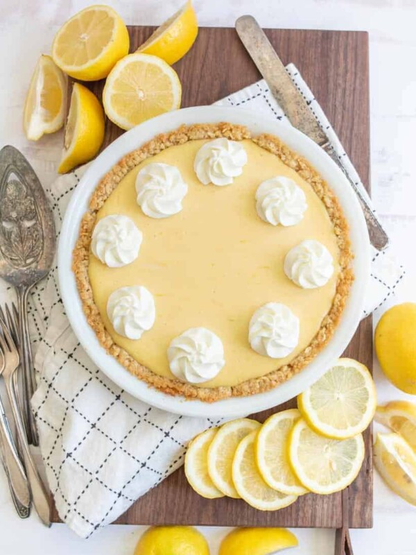top view of a lemon pie next to lemons and serving utensils