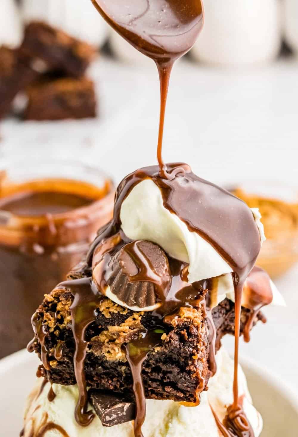 Picture of hot fudge being poured over a peanut butter brownie sundae