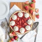 top view of a strawberry pie with strawberries and serving utensils around it