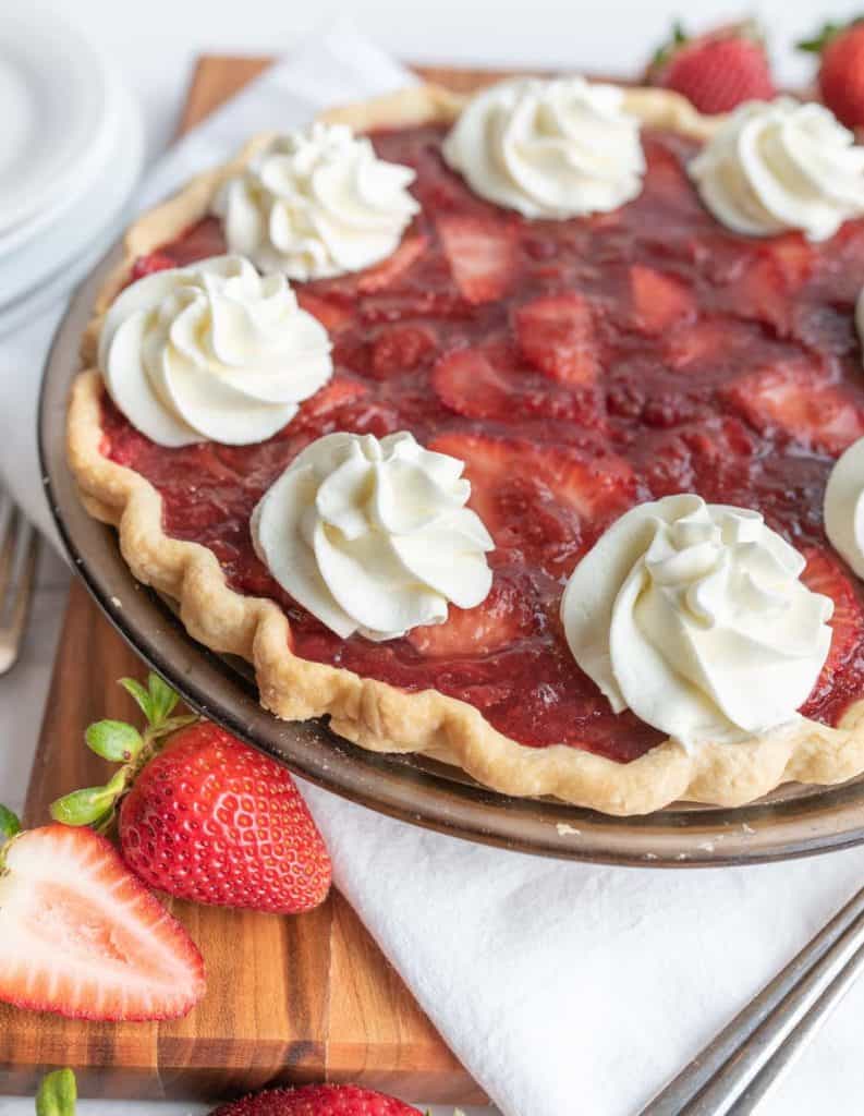 up close picture of a strawberry pie with dollops of whipped cream