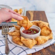 cream cheese wontons being dipped in sauce