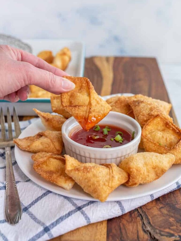 cream cheese wontons being dipped in sauce