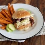 close up picture of pork chop sandwich on a plate with a side of sweet potato fries