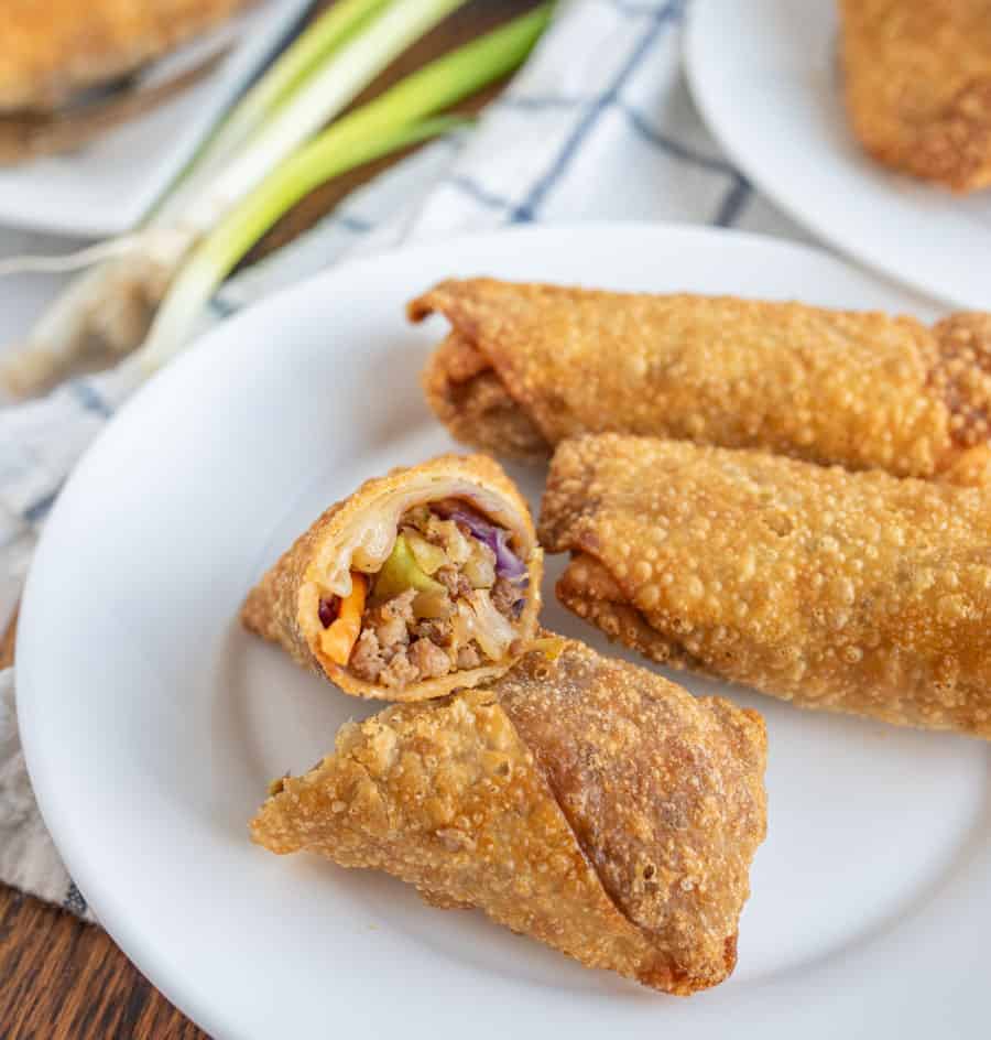 close up of an egg roll cut in half on a plate.