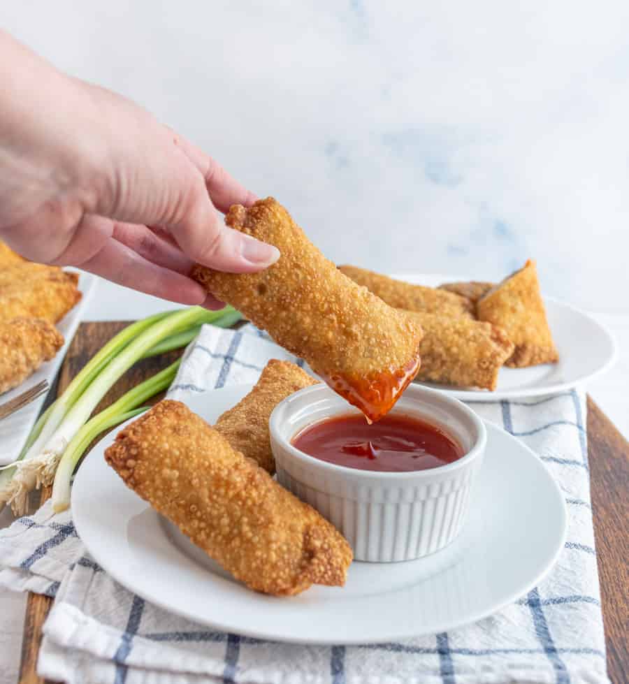 and egg roll being dipped in sauce.