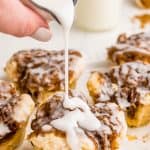 glaze being poured over monkey bread muffins