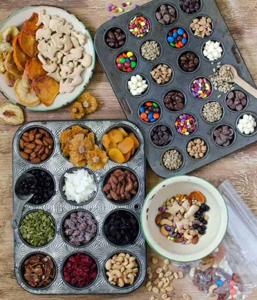 top view of ingredients in a bowl for trail mix next to muffin tins filled with ingredients for trail mix