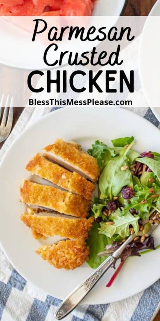 top view of a plate of parmesan crusted chicken sliced into pieces with a salad on the side and the words "parmesan crusted chicken" written at the top