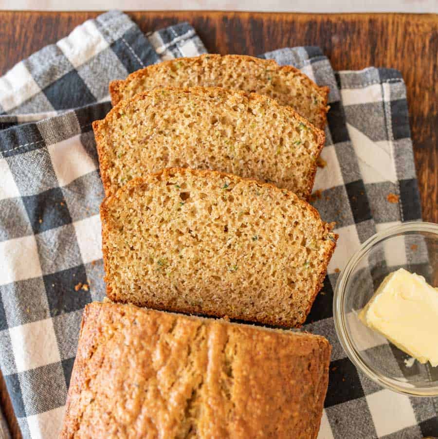 close up top view of slices of banana bread on a towel next to a bowl of butter