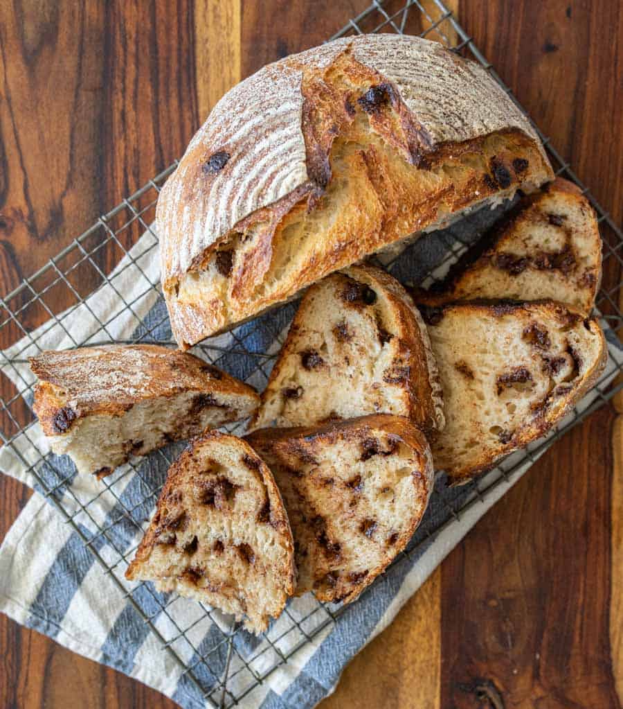 top view of chocolate chip sourdough bread cut into slices and half a loaf on a cooling rack