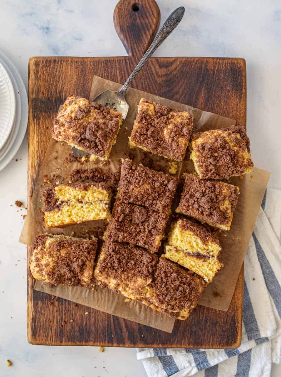 sliced coffee cake on top of parchment paper on top of a dark wood cutting board