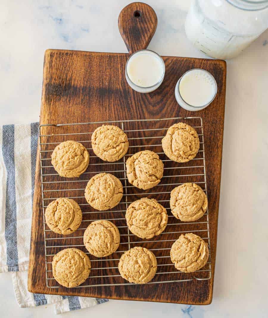 top view of peanut butter cookies on a cooling rack next to 2 glasses of milk