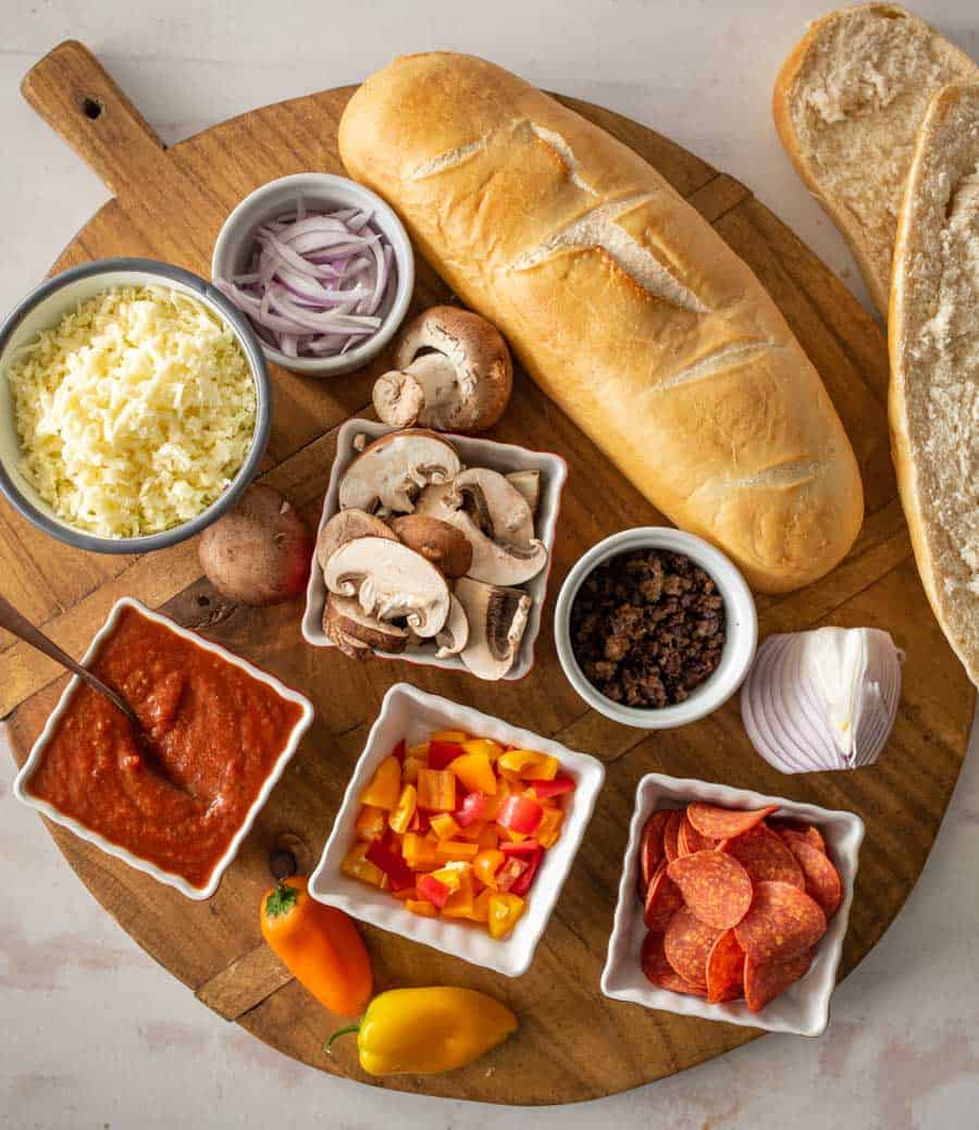 ingredients for French bread pizza sorted out on a cutting board