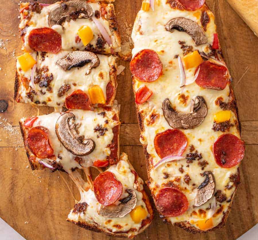 top view of two French bread pizzas, one of them being cut