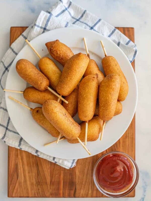 top view of a plate of corndogs with a bowl of ketchup next to it