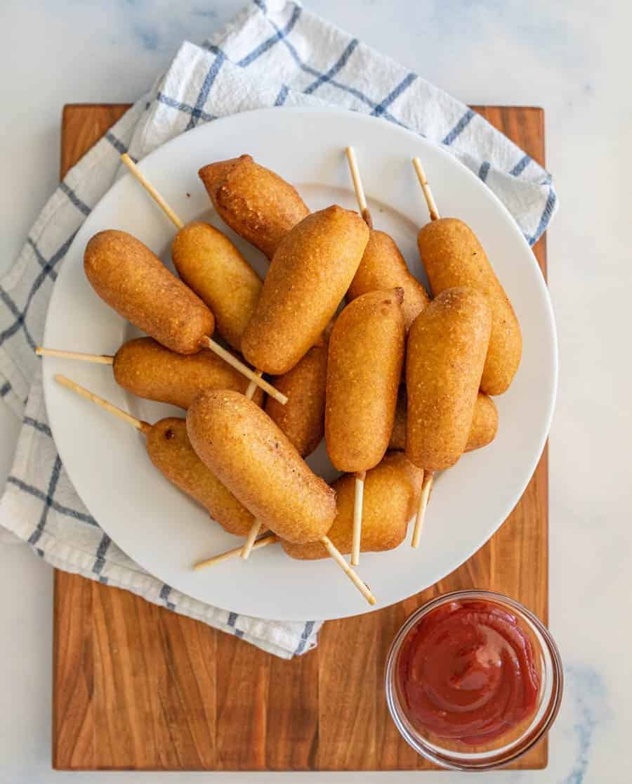 top view of a plate of corndogs with a bowl of ketchup next to it