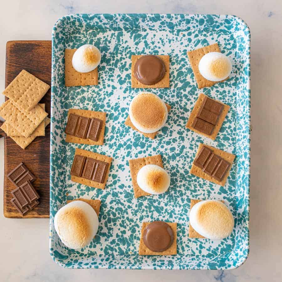 top view of a tray of toasted marshmallows and melted chocolate on graham crackers for smores.
