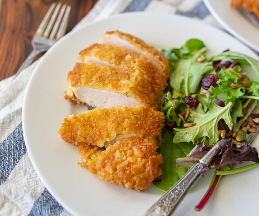 parmesan crusted chicken sliced into strips and salad with a fork on a plate