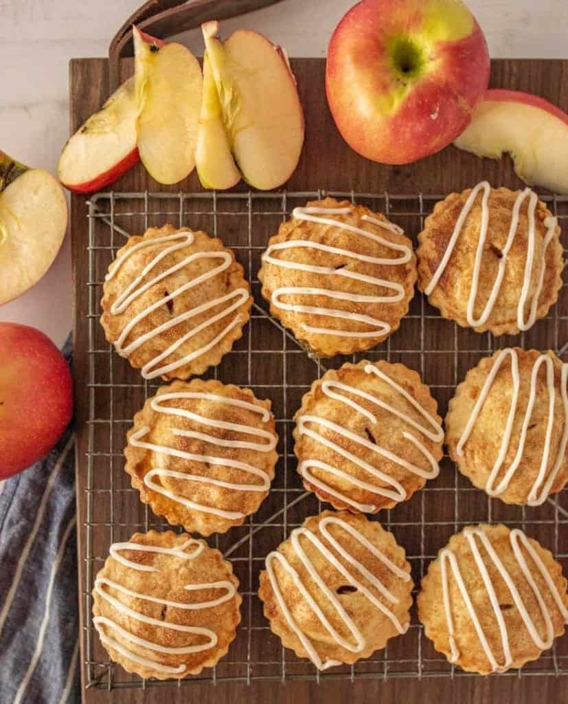 top view of apple hand pies on a cooling rack with apples on the side