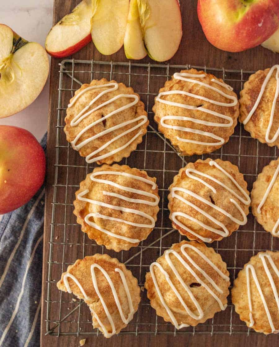 top view of apple hand pies on a cooling rack with apples on the side