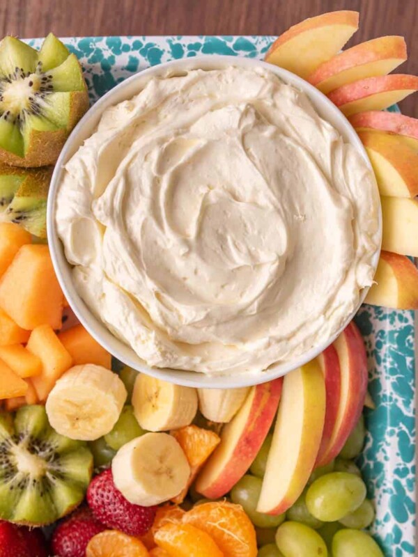 close up of a bowl of fruit dip and fruit on a tray