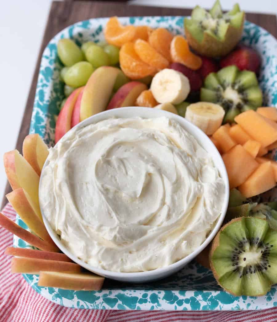 close up view of a bowl of fluffy fruit dip surrounded by cut up pieces of fruit