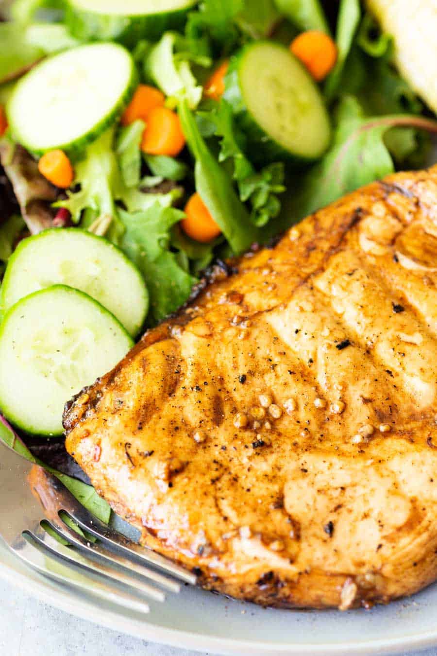 close up of balsamic chicken and a salad on a plate.
