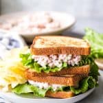 ham salad sandwiches stacked on a plate with chips