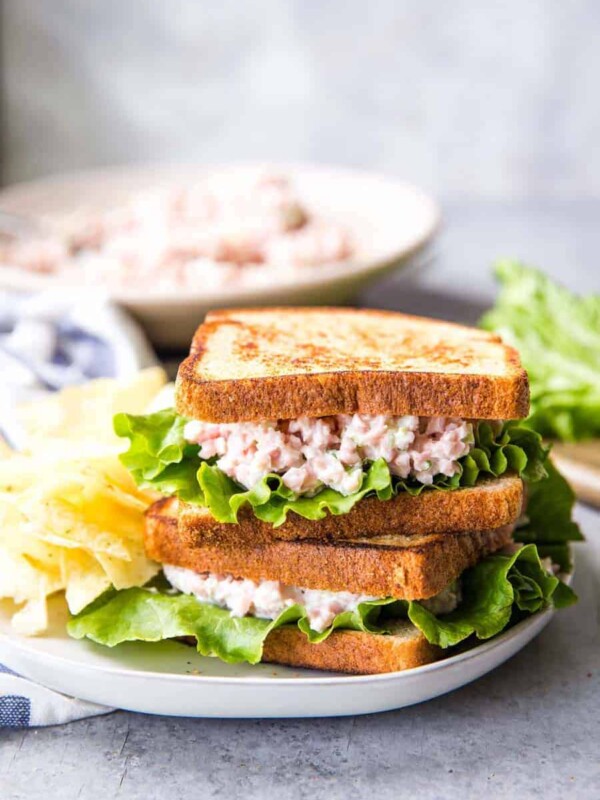 ham salad sandwiches stacked on a plate with chips