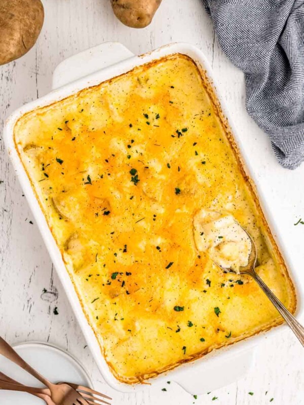 top view of a baking dish filled with potatoes au gratin and a serving spoon