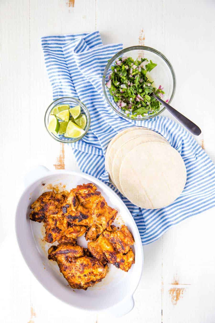 top view of chicken, tortillas, and limes for chicken tacos