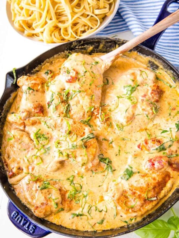 top view of Tuscan chicken in a skillet next to a bowl of pasta