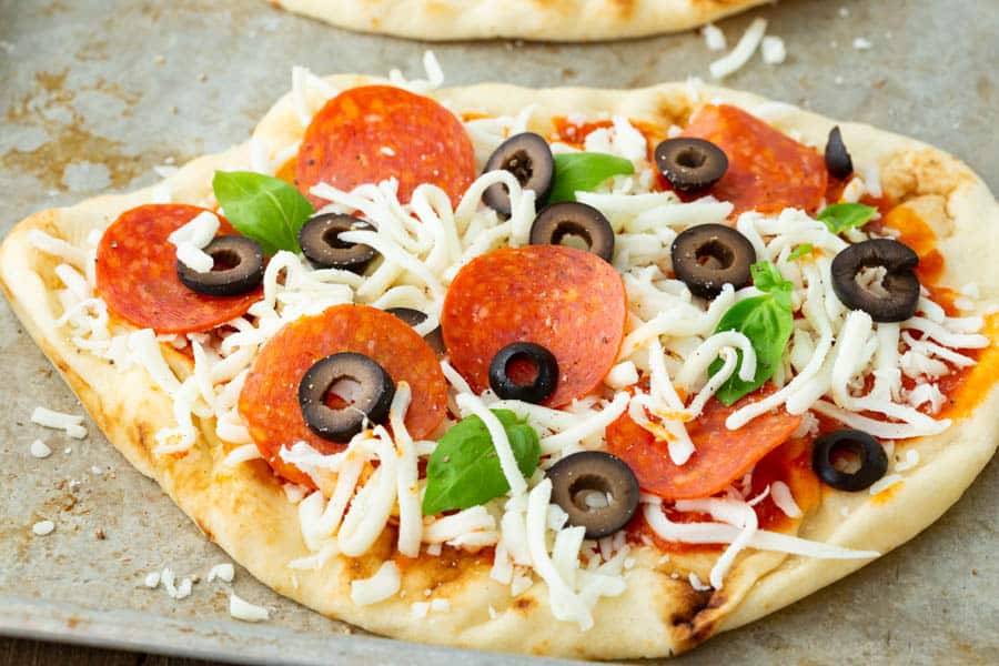 Flatbread pizza with pepperonis, olives, basil, and cheese