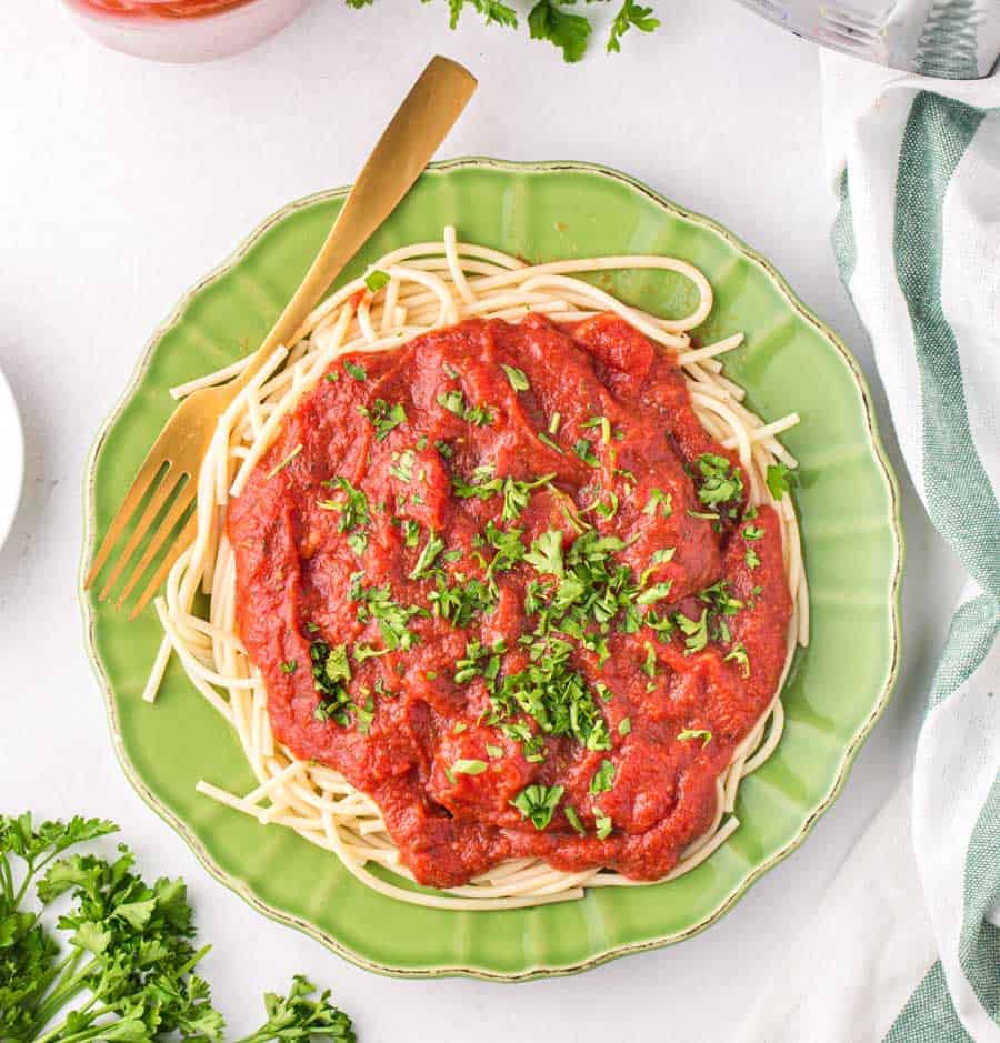 Top view of a green plate with spaghetti noodles and sauce on it.