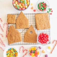 ascetic image of ginger bread house ingredients before construction - cookie pieces in house shape on wire rack and candies all around