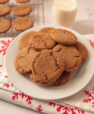 scene with ginger snap cookies on a rack and also piled on a plate with milk and festive napkins