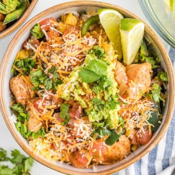 very close view of chicken burrito bowl to see detail of limes and cilantro and cheese avocados and tomatoes