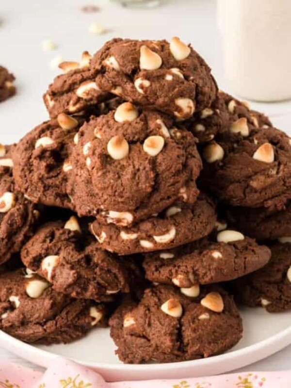 close view of chocolate colored cookies on a white plate with white chocolate chips in a big heap