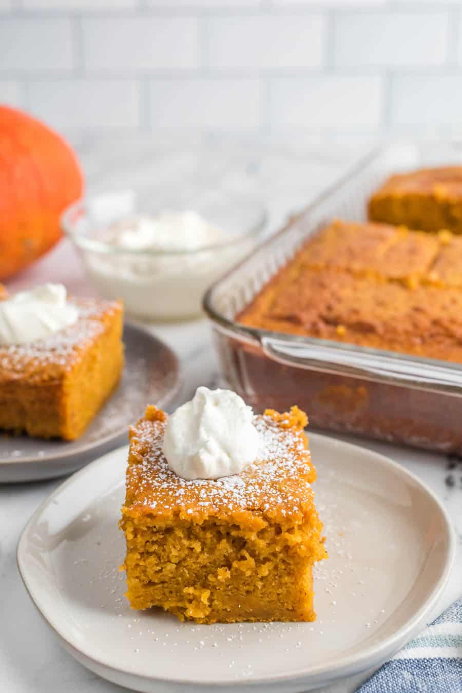 square servings of extra thick pumpkin cake on plates next to the baking dish