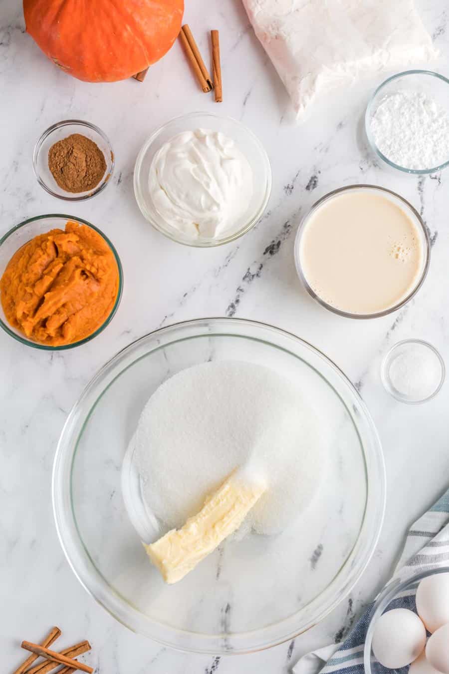 raw ingredients of the thick pumpkin cake in clear glass bowls on a marble table - the contrast of marble and sweet white ingredients and a deep orange pumpkin color